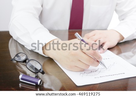 Businessman pointing his pen at mutual fund return and benchmark line chart and mutual fund rating. Mutual fund information with pen and eye glasses.