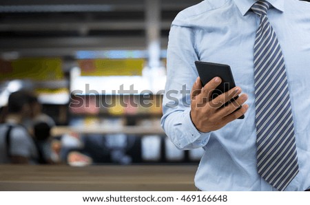 isolated business man hold the smartphone on shopping mall background
