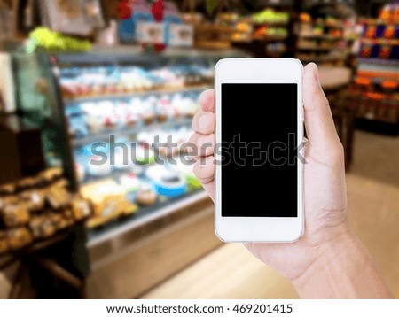 Hand holding blank screen mobile phone with blur coffee shop background