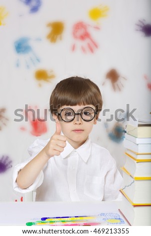 Schoolboy of 7 years old dressed in a shirt,sitting at the table with a pile of dictionaries