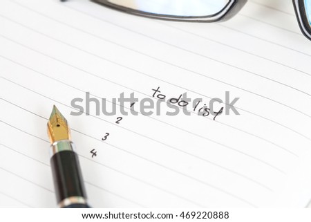 writing to do list on notebook page with pen on wood background