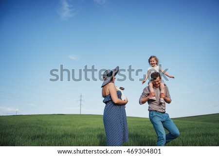 Happy family of three people hugging in the streets. The mother awaiting child. The smiling faces of women, men and children. Children play with their parents.