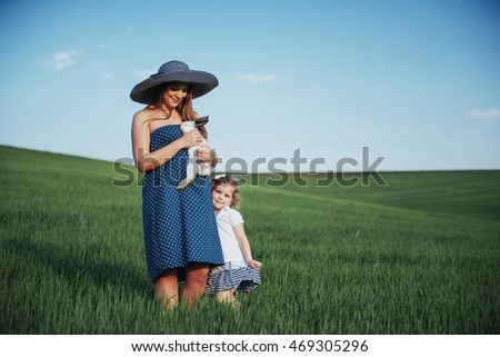 Happy mother and baby with rabbit on hands in field
