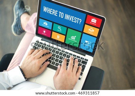 People using laptop in an office and WHERE TO INVEST? concept on screen