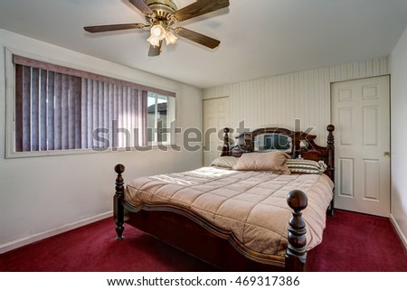 Bedroom interior with nice carved wooden bed and red carpet floor. Northwest, USA