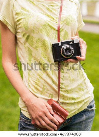 Young beautiful woman with beautiful figure, posing with retro camera making photos, taking pictures. Young photographer and vintage camera outdoors