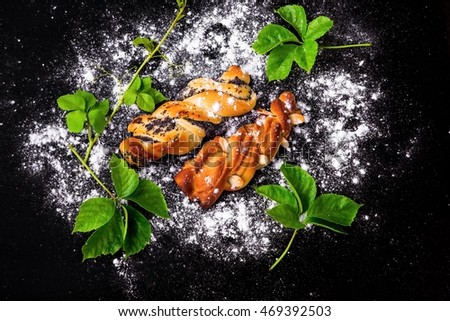 Festive Czech republic sweet pastry with almond or poppy seed braided from yest dough on black background sprinkled with powder sugar and vivid green leaf