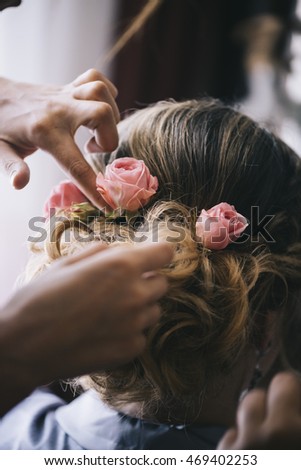 wedding preparations. Young beautiful bride getting her hairstyle, braiding roses in hair