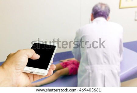 Man use mobile phone, blur image of doctor treating children patients as background.