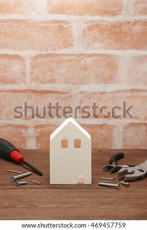 Miniature house and tools in front of brick wall. Concept of repair house. Repair and construction of the house.