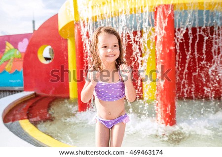 Girl under splashing fountain. Summer heat and water.