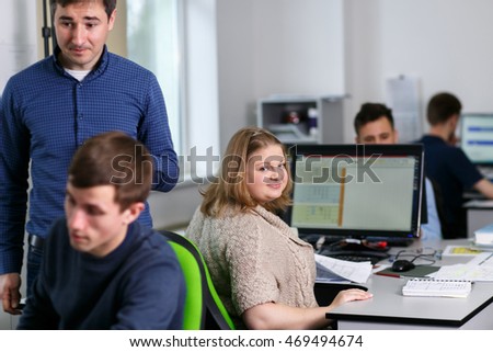 Pretty woman looks over her shoulder while sitting at the working table