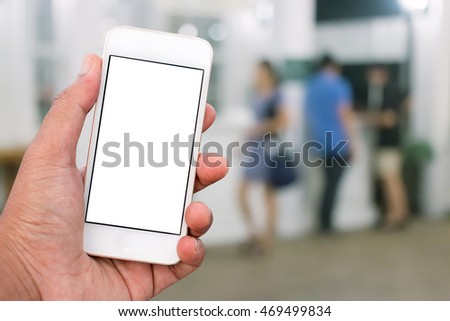 Hand holding mobile smart phone with blank screen in vertical position, blurred people background - mockup template