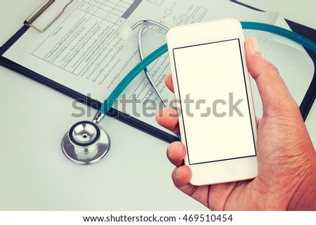 Hand holding mobile smart phone with blank screen in vertical position, Medical stethoscope with clipboard and pen - mockup template