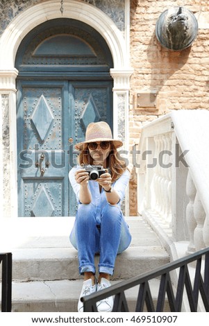 Full length portrait of smiling woman taking pictures with her vintage camera while exploring Venice. 