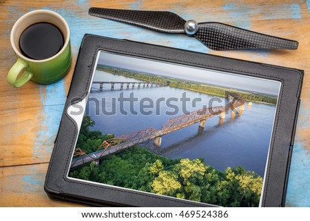 aerial landscape photography concept - reviewing pictures of Chain of Rocks Bridge over Mississippi River on tablet with a drone propeller and coffee