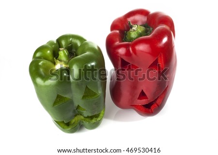 Food art creative concept. Halloween scary faces carved into red and green capsicum vegetables isolated over a white background.