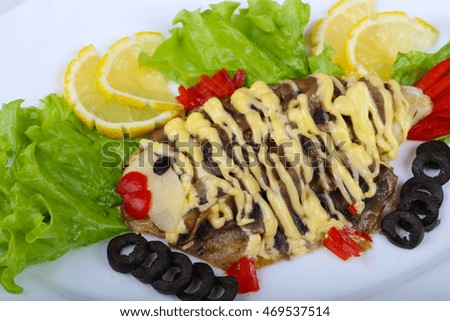 Tilapia fish fillet styled with salad, lemon and olives