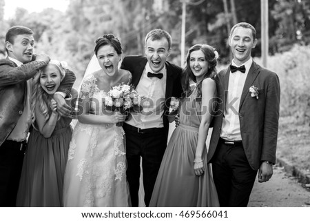 Newlyweds with groomsmen & bridesmaids having fun outdoors