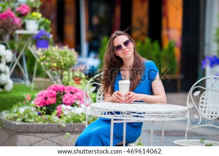 Happy young urban woman with modern mobile and coffee at outdoor cafe in Europe. Caucasian tourist enjoy her european vacation in empty city