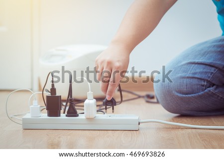 Closeup at the hands of men unplugged plug to save on energy Royalty-Free Stock Photo #469693826