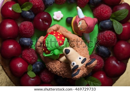 Homemade cake with mastic figures and berries.