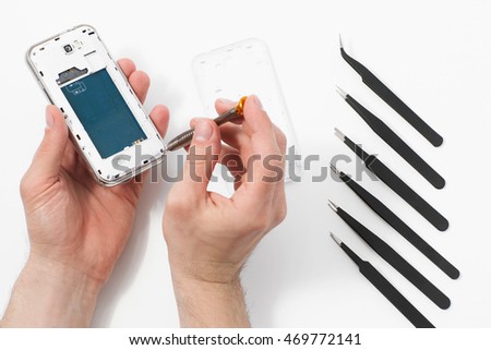 Smartphone disassembling with special tools. Phone repair service, male hand removing plastic case from communication device, white background with disassembling instruments