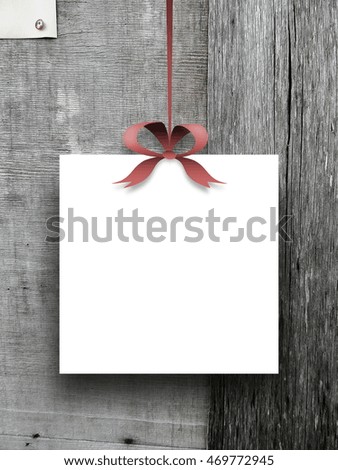 Close-up of one blank square frame hanged by ribbon against gray weathered wooden boards background