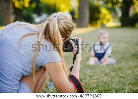 Woman photographer photographing the baby to spend outside in the park