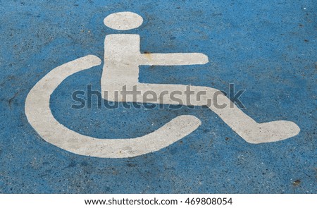 Handicapped or disabled parking sign painted on blue asphalt
