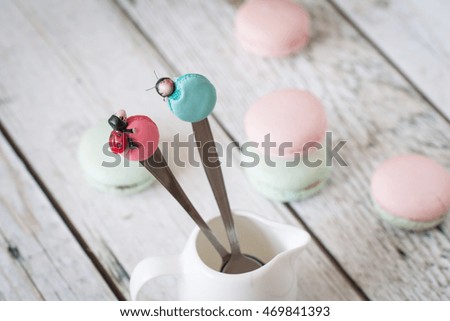 Funny spoons with macarons and ladybugs with french macarons on background