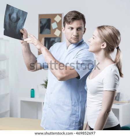Physiotherapist and patient analyzing x-ray of hip joint