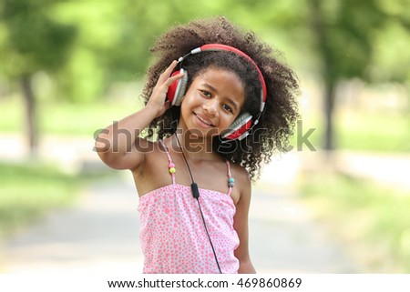 Cute African American girl listening music on street