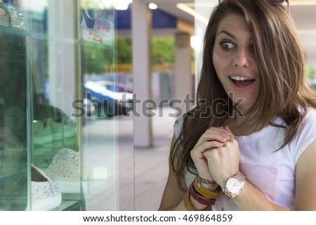 Excited female customer watching shop window displays outdoors
