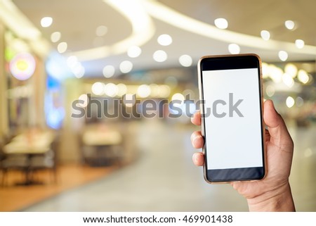 Hand holding blank screen of smartphone device in department store.