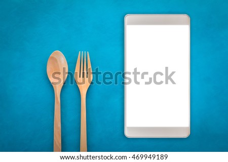 Wooden Spoon and fork with smartphone on color background