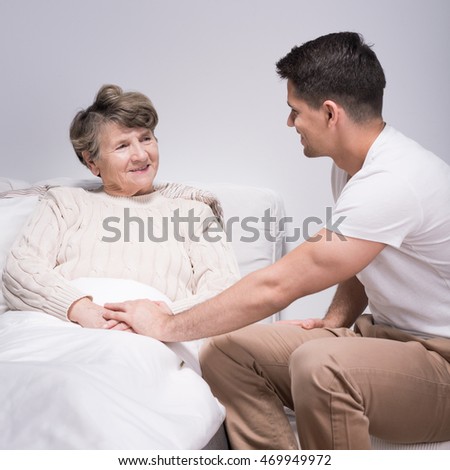 Photo of young man helping his ill grandmother