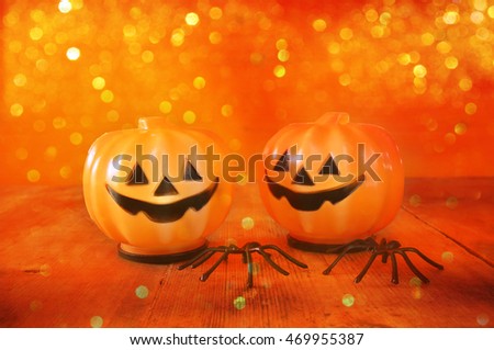 Halloween holiday concept. Cute pumpkins on wooden table. Glitter lights overlay
