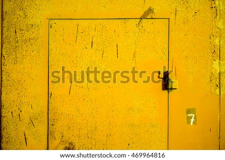 Big metal door with rusty cracked paint and dark lock. Yellow metal door with cracked paint and dark vertical scratch. high resolution