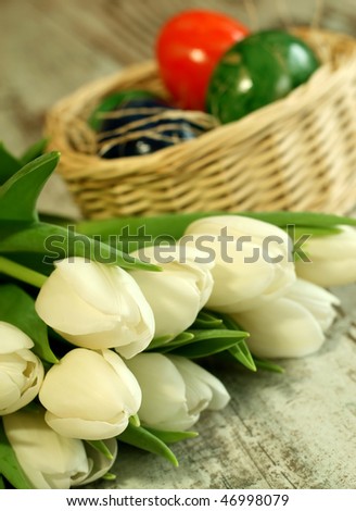 white tulips and easter eggs in  wattled basket
