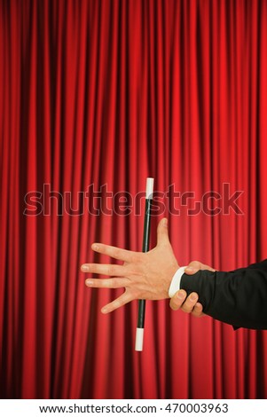 Magician performing simple trick with magic wand on stage