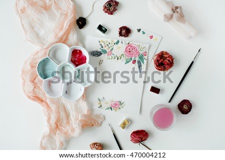 Workspace. Pink and red roses painted with watercolor, paintbrush and roses on white wooden background. Overhead view. Flat lay, top view