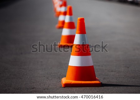 bright orange traffic cones standing in a row on dark asphalt Royalty-Free Stock Photo #470016416
