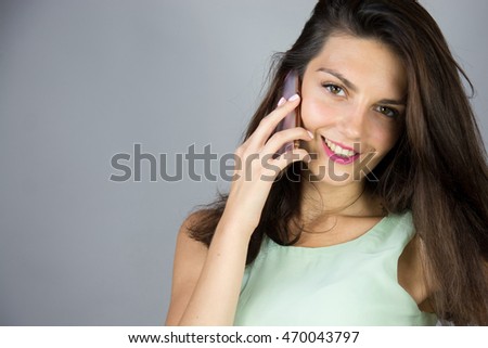 Happy emotional young woman talking on mobile phone on grey background