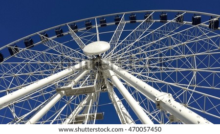 Ferris wheel in white and blue on a background of blue sky.