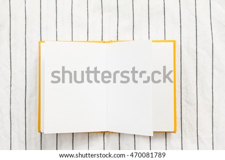 Opened blank spread notebook on blue and white stripe pattern cloth background.
