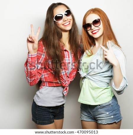 two young girl friends standing together and having fun. Showing signs with hands. Looking at camera