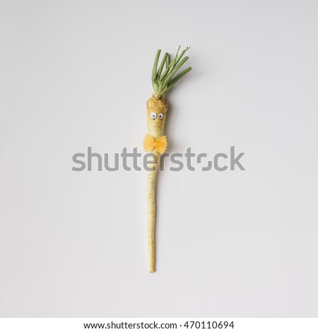 Parsley root with eyes and bowtie on white background. Minimal concept