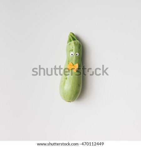 Zucchini with eyes and bowtie on white background. Minimal concept