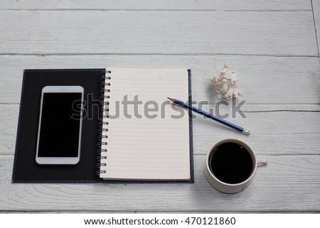 Blank notebook with pencil and mobile-phone,cup coffee on table background copy space